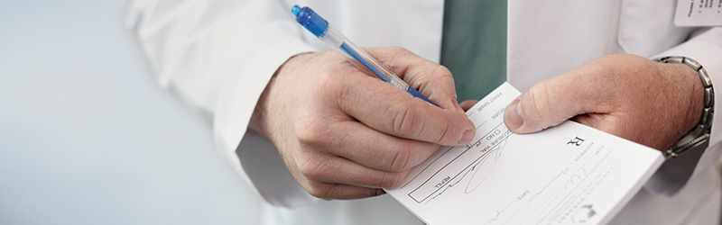 hands of pharmacist writing on prescription pad