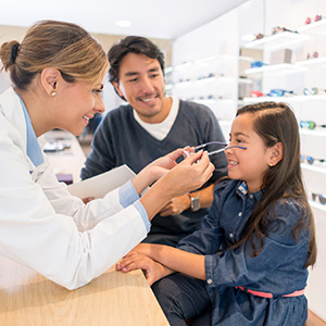 Little girl trying on glasses at optometrist office