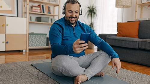 Man sitting on yoga mat in his living room