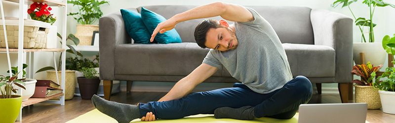 man doing yoga in front of computer