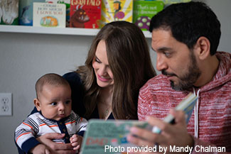 Father and mother read a book to their baby