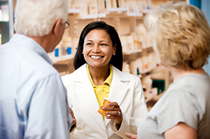 pharmacist holding prescription talking to older man and woman