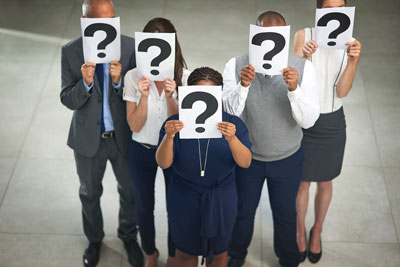 five people standing in lobby holding question marks in front of faces