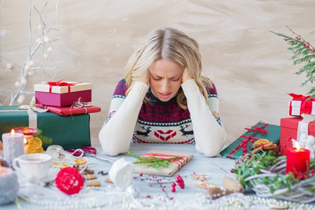 woman at table stressed over Christmas gifts