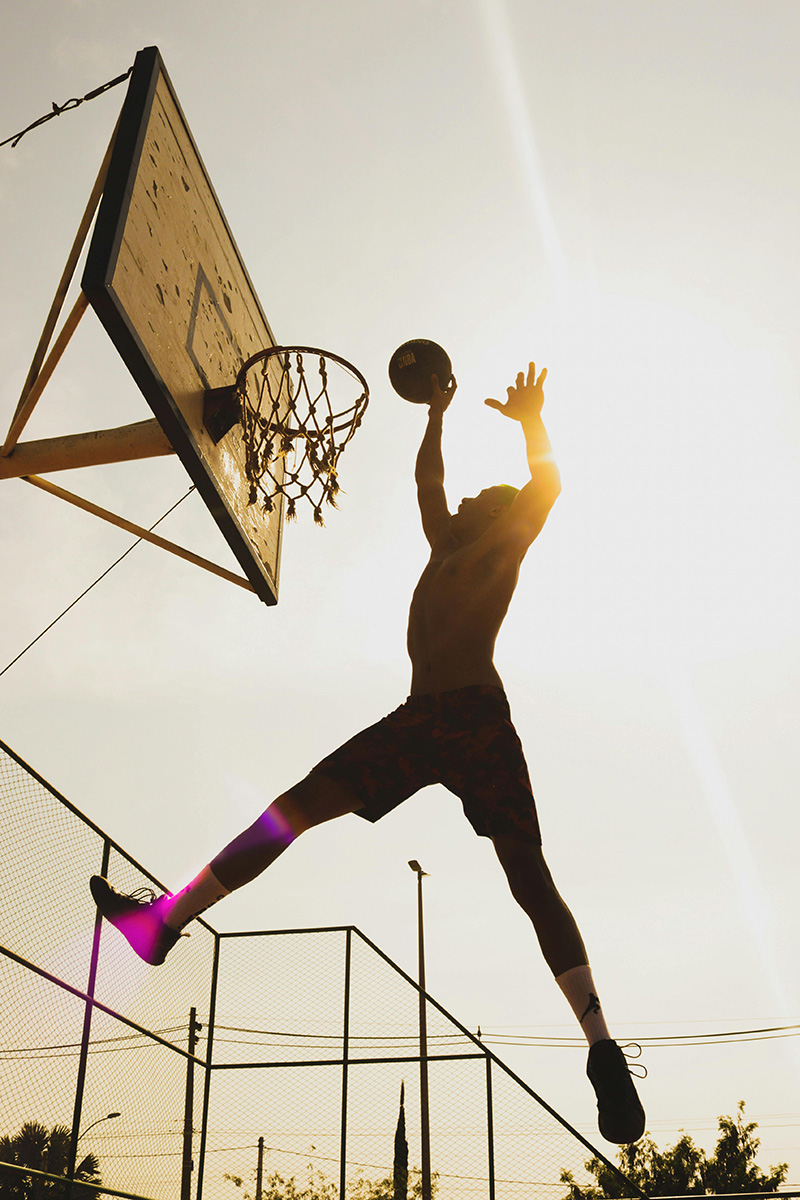 man slam dunking basketball in the basketball hoop