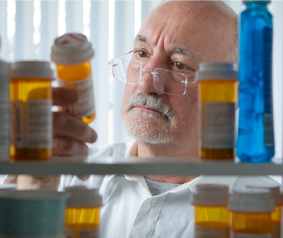 older man looking at prescription bottle