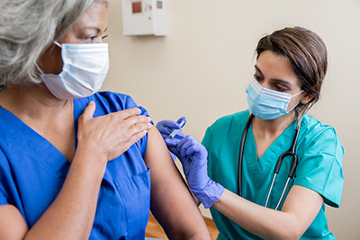 woman receiving vaccination shot from female health care professional