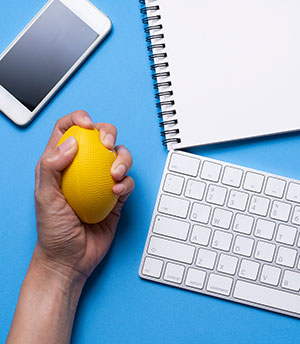 cluttered desk focus on hand squeezing stress ball