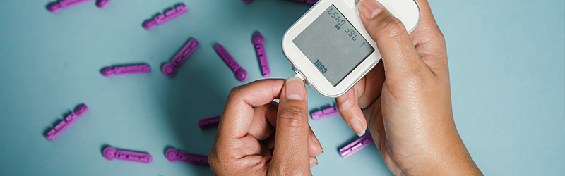 focus on person's checking insulin levels with glucose meter and lancet strips